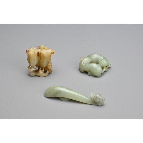 73 - THREE CHINESE CARVED JADE ITEMS. To include a celadon lion cub group; A celadon dragon head belt hoo... 