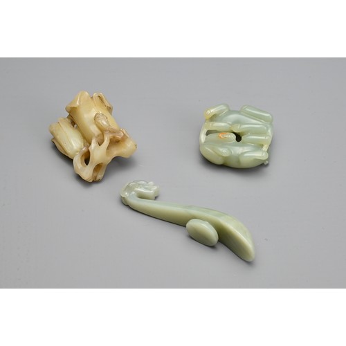 73 - THREE CHINESE CARVED JADE ITEMS. To include a celadon lion cub group; A celadon dragon head belt hoo... 