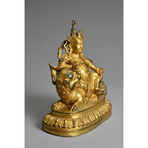 181 - A SINO-TIBETAN GILT-BRONZE FIGURE OF VAISHRAVANA, cast seated atop a lion holding a rat in his left ... 