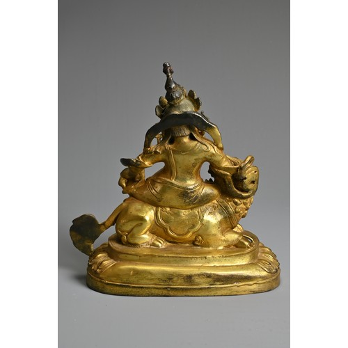 181 - A SINO-TIBETAN GILT-BRONZE FIGURE OF VAISHRAVANA, cast seated atop a lion holding a rat in his left ... 