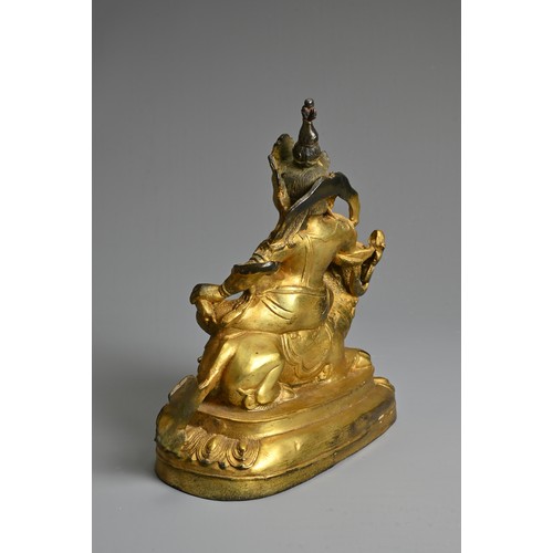 181 - A SINO-TIBETAN GILT-BRONZE FIGURE OF VAISHRAVANA, cast seated atop a lion holding a rat in his left ... 