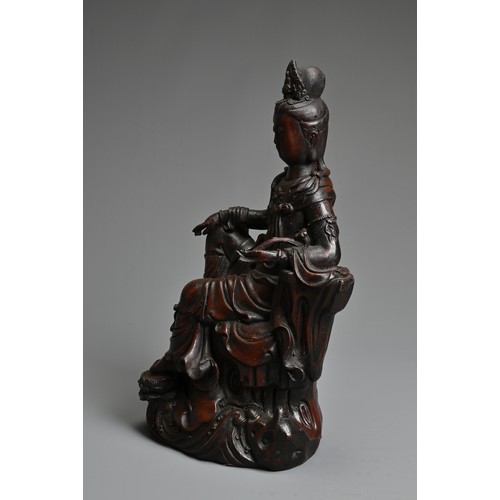 179 - A CHINESE PATINATED BRONZE MODEL OF A SEATED GUANYIN. In dark-brown patination, cast reclining on dr... 