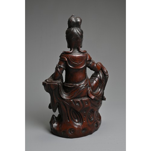 179 - A CHINESE PATINATED BRONZE MODEL OF A SEATED GUANYIN. In dark-brown patination, cast reclining on dr... 