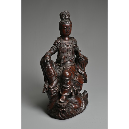 179 - A CHINESE PATINATED BRONZE MODEL OF A SEATED GUANYIN. In dark-brown patination, cast reclining on dr... 