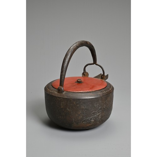 238 - A 20TH CENTURY JAPANESE CAST IRON CHOSHI (SAKE EWER), set on tripod feet with red lacquered wood cov... 