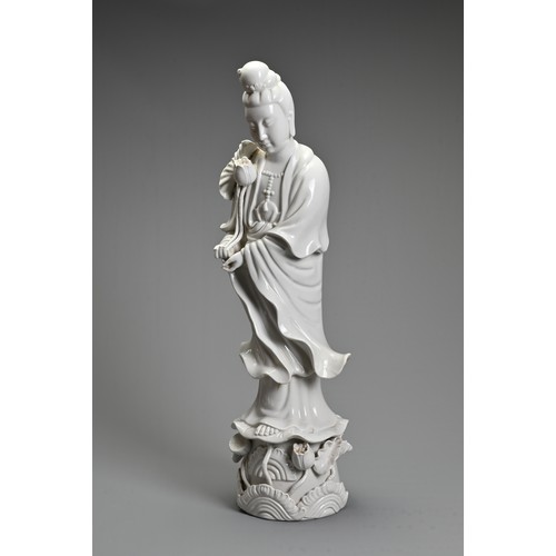 105 - A CHINESE BLANC-DE-CHINE FIGURE OF GUANYIN. The moulded figure standing on a lotus leaf pedestal, ho... 