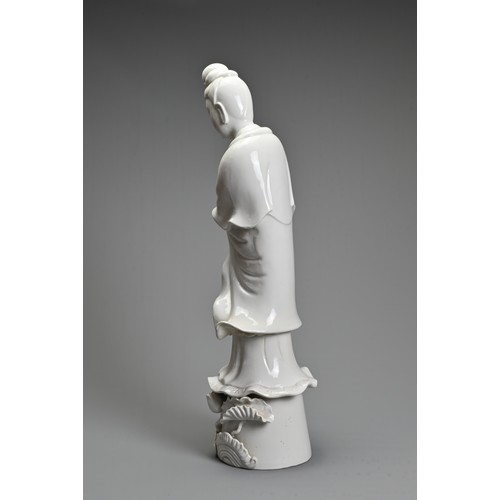 105 - A CHINESE BLANC-DE-CHINE FIGURE OF GUANYIN. The moulded figure standing on a lotus leaf pedestal, ho... 