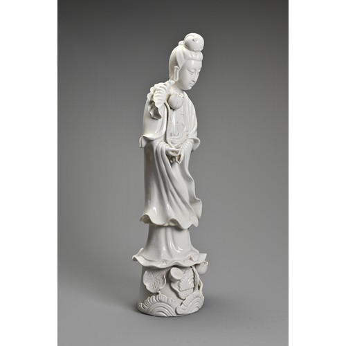 105 - A CHINESE BLANC-DE-CHINE FIGURE OF GUANYIN. The moulded figure standing on a lotus leaf pedestal, ho... 