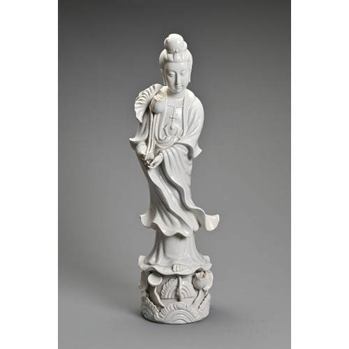 105 - A CHINESE BLANC-DE-CHINE FIGURE OF GUANYIN. The moulded figure standing on a lotus leaf pedestal, ho... 