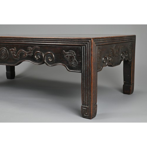 204 - A CHINESE HARDWOOD LOW RECTANGULAR TABLE, QING DYNASTY. The frieze carved with bats, ruyi clouds, dr... 