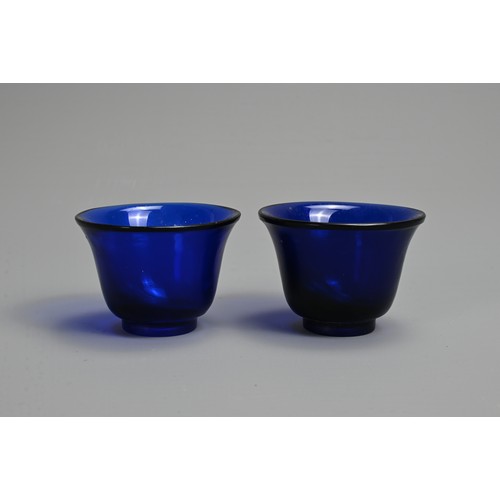 274 - A PAIR OF CHINESE BLUE PEKING GLASS WINE CUPS, LATE QING DYNASTY. Bell shaped cups on thick circular... 