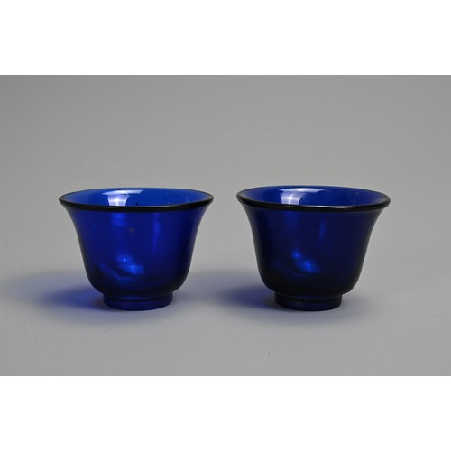 274 - A PAIR OF CHINESE BLUE PEKING GLASS WINE CUPS, LATE QING DYNASTY. Bell shaped cups on thick circular... 