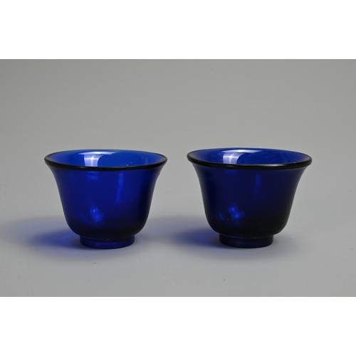 274 - A PAIR OF CHINESE BLUE PEKING GLASS WINE CUPS, LATE QING DYNASTY. Bell shaped cups on thick circular... 