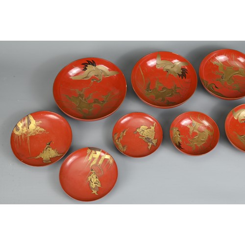 287 - A GROUP OF EIGHT 20TH CENTURY JAPANESE RED LACQUER SAKE CUPS IN SIZES. Decorated in gold maki-e on a... 