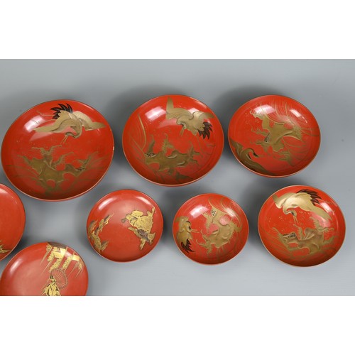 287 - A GROUP OF EIGHT 20TH CENTURY JAPANESE RED LACQUER SAKE CUPS IN SIZES. Decorated in gold maki-e on a... 