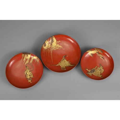 287 - A GROUP OF EIGHT 20TH CENTURY JAPANESE RED LACQUER SAKE CUPS IN SIZES. Decorated in gold maki-e on a... 