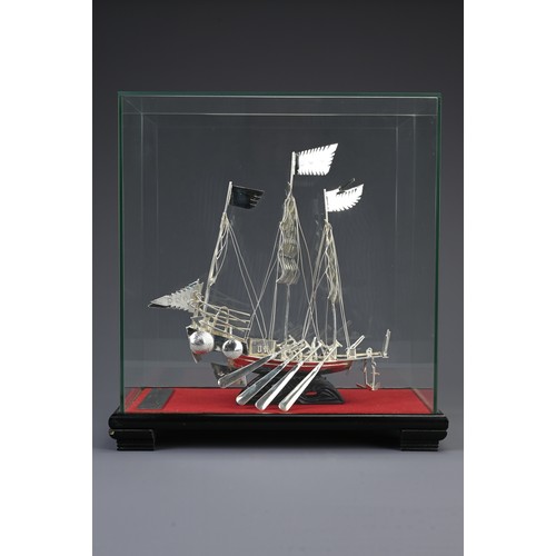 62 - A CHINESE WHITE METAL COMMEMORATIVE MODEL OF A JUNK BOAT, 20TH CENTURY. Mounted in a glass case on w... 