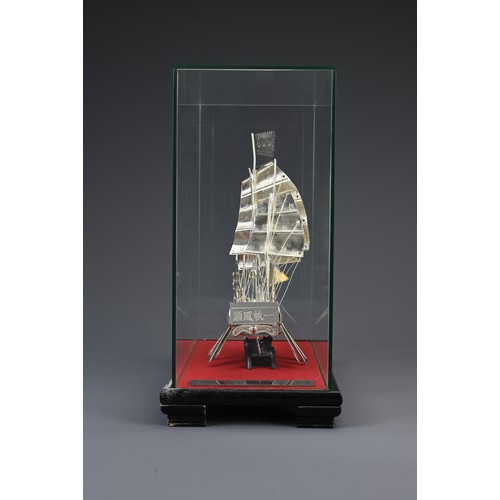 62 - A CHINESE WHITE METAL COMMEMORATIVE MODEL OF A JUNK BOAT, 20TH CENTURY. Mounted in a glass case on w... 