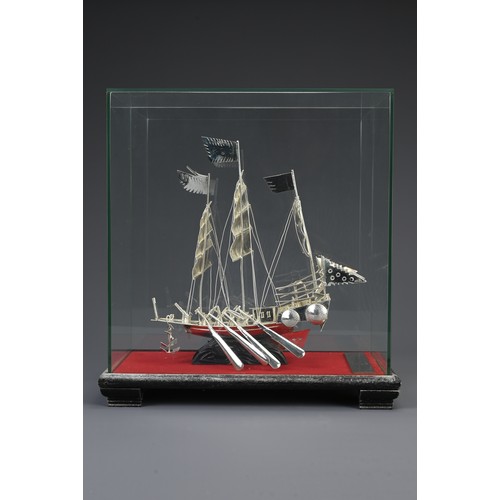 62 - A CHINESE WHITE METAL COMMEMORATIVE MODEL OF A JUNK BOAT, 20TH CENTURY. Mounted in a glass case on w... 