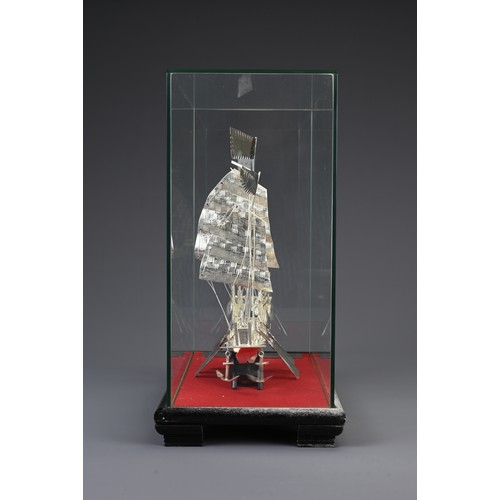 62 - A CHINESE WHITE METAL COMMEMORATIVE MODEL OF A JUNK BOAT, 20TH CENTURY. Mounted in a glass case on w... 