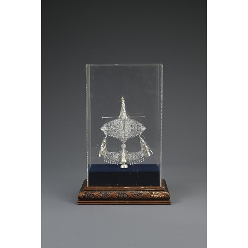 70 - A MALAYSIAN WHITE METAL ORNAMENT, 20TH CENTURY. In a perspex cased box on wooden stand with plaque r... 