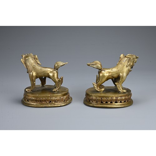 85 - A MIRRORED PAIR OF TIBETAN BRONZE TEMPLE LIONS, 19/20TH CENTURY. Each standing with their tongues ou... 