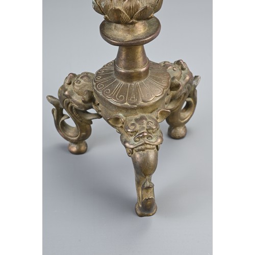 87 - A CHINESE BRONZE PRICKET CANDLESTICK, 20TH CENTURY. Raised on three lion form feet with single lotus... 