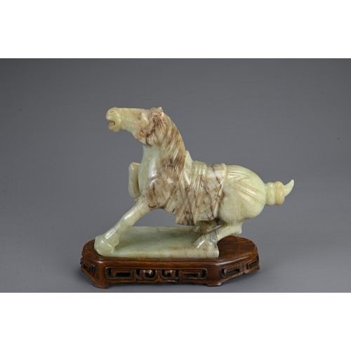 359 - A CHINESE CARVED JADE MODEL OF A PRANCING HORSE, 20TH CENTURY. Mounted on a carved and pierced woode... 