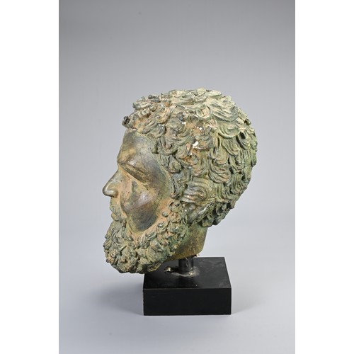 98 - A DECORATIVE CAST BRONZE HEAD. Hollow cast male head, Greek or Roman in style on a display stand. He... 