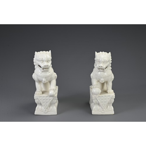 160 - A PAIR OF CHINESE WHITE GLAZED PORCELAIN GUARDIAN LIONS, 20TH CENTURY. Seated on a rectangular form ... 