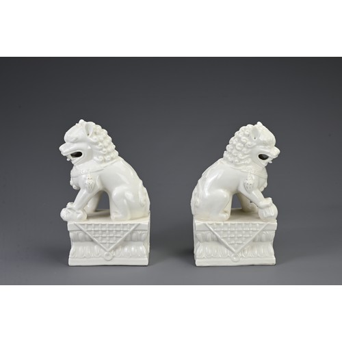 160 - A PAIR OF CHINESE WHITE GLAZED PORCELAIN GUARDIAN LIONS, 20TH CENTURY. Seated on a rectangular form ... 