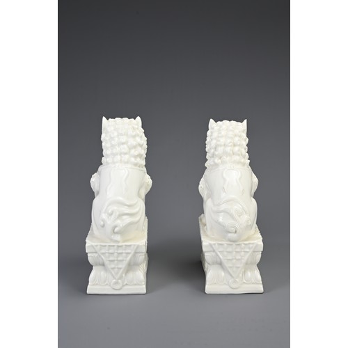 160 - A PAIR OF CHINESE WHITE GLAZED PORCELAIN GUARDIAN LIONS, 20TH CENTURY. Seated on a rectangular form ... 