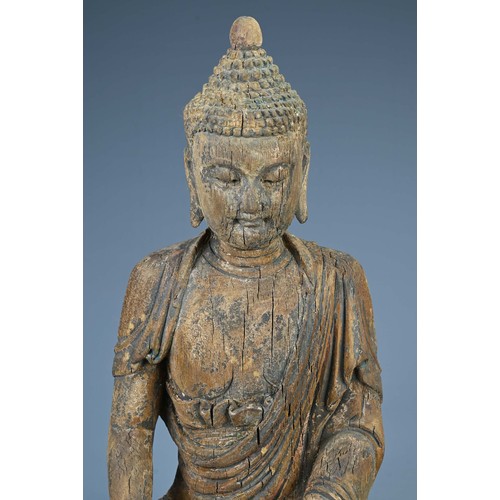 181 - A CARVED WOODEN FIGURE OF SEATED BUDDHA, MING DYNASTY OR LATER. The figure dressed in robes with ser... 