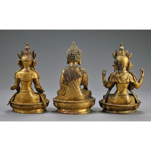 188 - A TRIO OF TIBETAN BRONZE SEATED BUDDHAS ON STAND. The deities dressed in robes adorned with jewels o... 