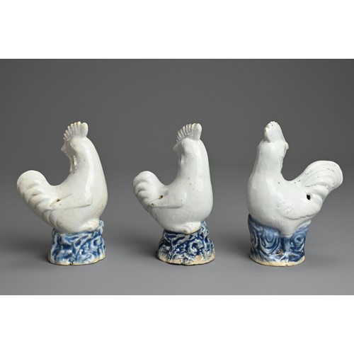 6 - THREE CHINESE BLUE AND WHITE PORCELAIN MODELS OF ROOSTERS, QING DYNASTY. Each standing on a rockwork... 