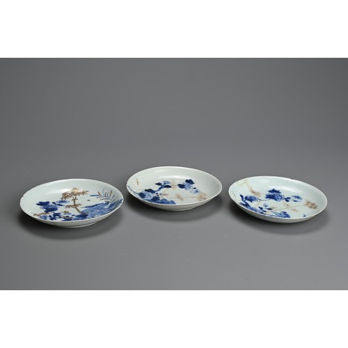 239 - THREE CHINESE BLUE AND WHITE GILT DECORATED SAUCERS, 18TH CENTURY. Each featuring a bird on rockwork... 