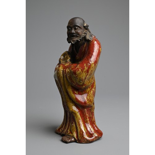 249 - A CHINESE GLAZED SHIWAN POTTERY MODEL OF DAMO, 19/20TH CENTURY. Standing bare foot dressed in robe, ... 