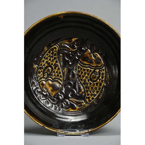 260 - A CHINESE CIZHOU STYLE CARP DISH, 20TH CENTURY. Moulded and incised with two carp amongst waves, enr... 