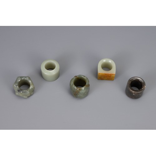 317 - FIVE CHINESE CARVED JADE ARCHERS RINGS, to include bamboo form, lotus form, and three others, larges... 