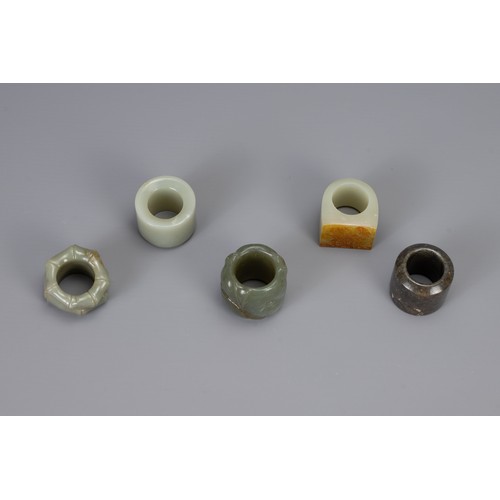 317 - FIVE CHINESE CARVED JADE ARCHERS RINGS, to include bamboo form, lotus form, and three others, larges... 