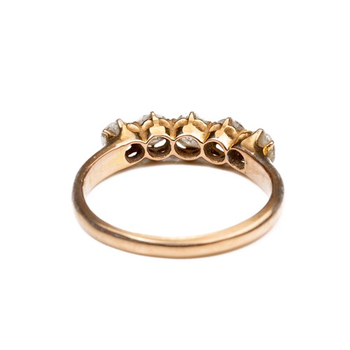 42 - A HIGH CARAT ROSE GOLD DIAMOND RING, MID 20TH CENTURY. With a row of five round cut diamonds. Unmark... 