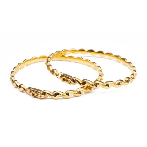 50 - A PAIR OF HIGH CARAT YELLOW GOLD HINGED TWISTED BRACELETS, MID 20TH CENTURY. Unmarked but testing as... 