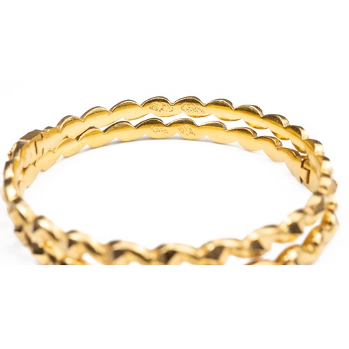 50 - A PAIR OF HIGH CARAT YELLOW GOLD HINGED TWISTED BRACELETS, MID 20TH CENTURY. Unmarked but testing as... 