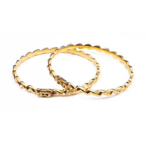 50 - A PAIR OF HIGH CARAT YELLOW GOLD HINGED TWISTED BRACELETS, MID 20TH CENTURY. Unmarked but testing as... 