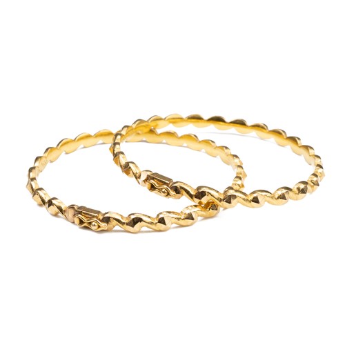 51 - A PAIR OF HIGH CARAT YELLOW GOLD HINGED TWISTED BRACELETS, MID 20TH CENTURY. Unmarked but testing as... 