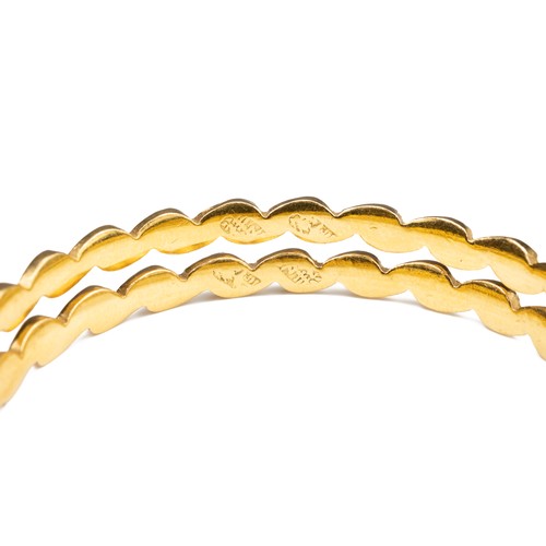 51 - A PAIR OF HIGH CARAT YELLOW GOLD HINGED TWISTED BRACELETS, MID 20TH CENTURY. Unmarked but testing as... 