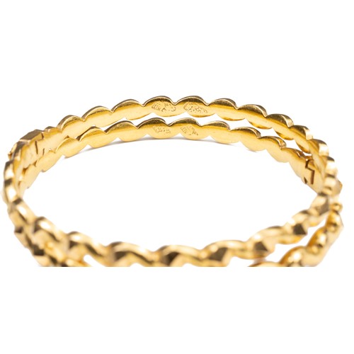 51 - A PAIR OF HIGH CARAT YELLOW GOLD HINGED TWISTED BRACELETS, MID 20TH CENTURY. Unmarked but testing as... 