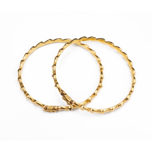 51 - A PAIR OF HIGH CARAT YELLOW GOLD HINGED TWISTED BRACELETS, MID 20TH CENTURY. Unmarked but testing as... 