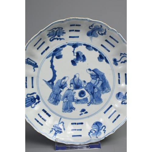 87 - A CHINESE BLUE AND WHITE PORCELAIN DISH, EARLY 18TH CENTURY. Of lobed form decorated with scholars a... 