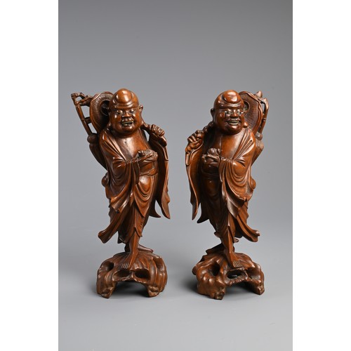 198 - A PAIR OF CHINESE CARVED WOODEN FIGURES, EARLY 20TH CENTURY. A mirrored pair each holding a bat and ... 